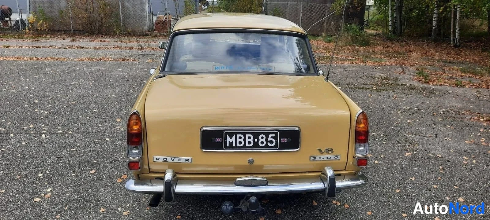 Takaa: Auton takaosa suoraan takaa: keltainen takakansi, ROVER- ja V8 3500 -merkinnät, kromipuskuri ja rekisterikilpi.