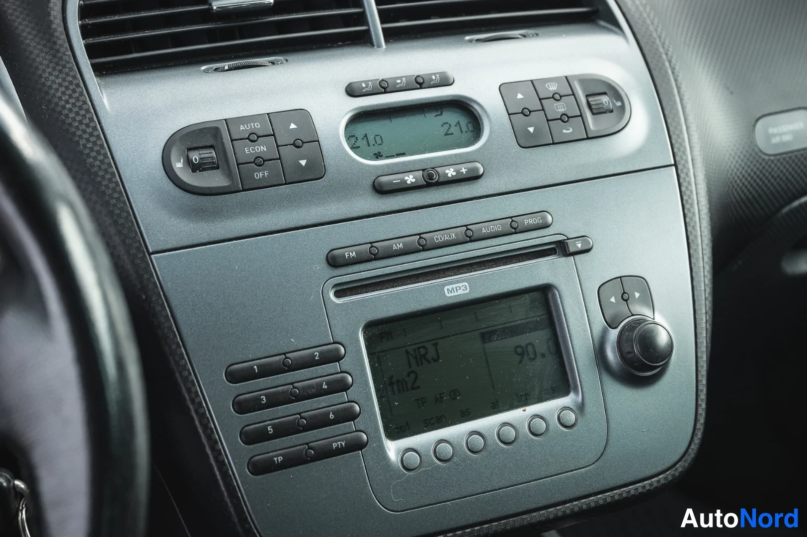 Muu: Lähikuva kojelaudan keskiosasta: automaattinen ilmastointipaneeli ja radio-näyttö.