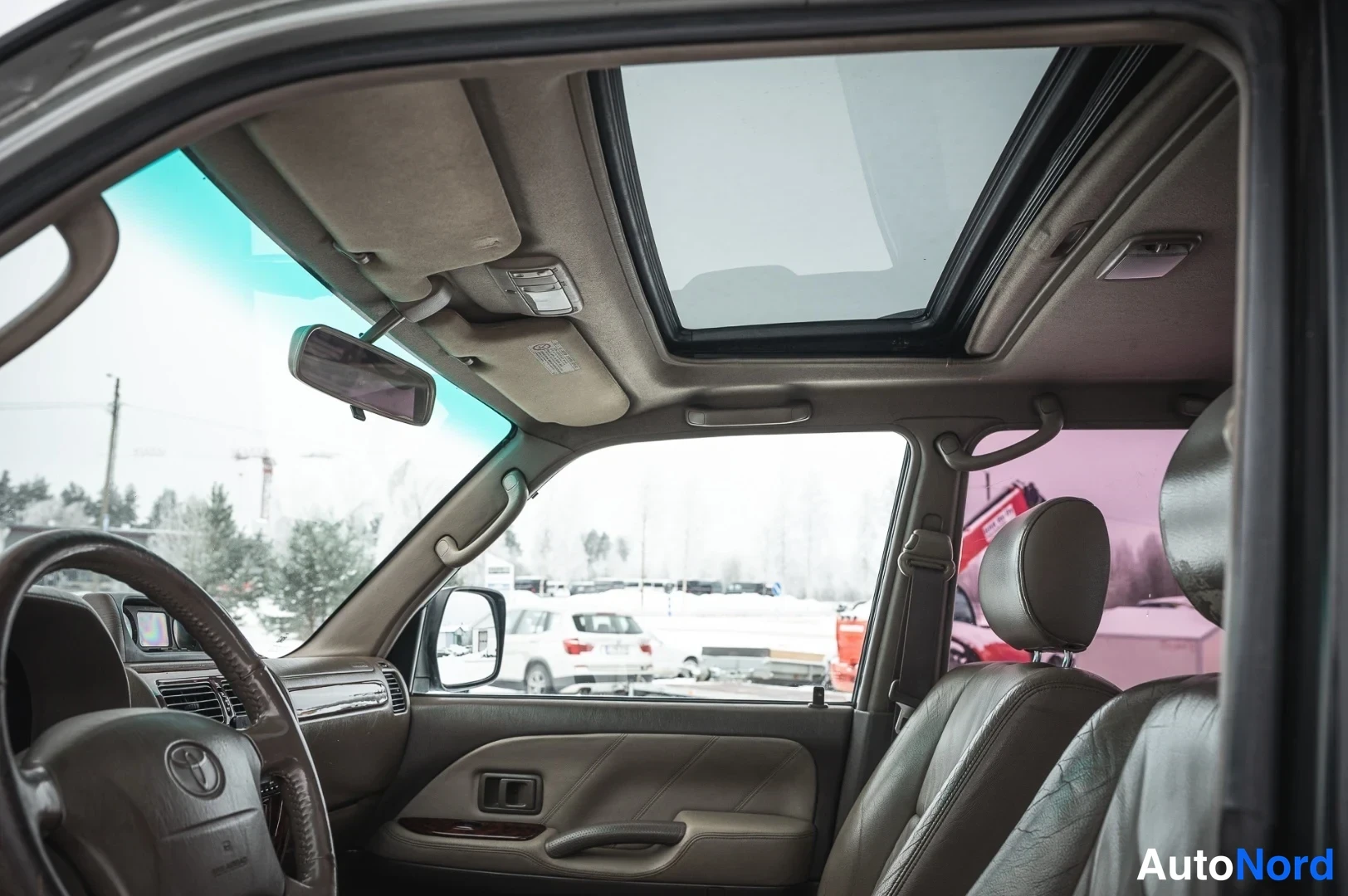 Muu: Ohjaamo sisäältä katsottuna: avattava kattoikkuna (sunroof), tumma kattopaneeli ja ruskeanahkainen sisusta.