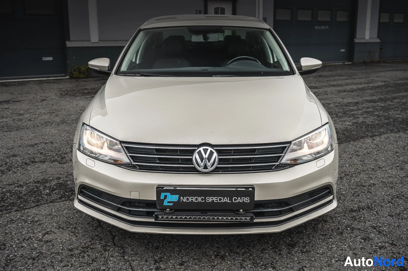 Edestä: Volkswagen Jetta, etukuva: beige thiili, VW-merkki etusäleikössä ja Nordic Special Cars -kyltti rekisterin paikalla.