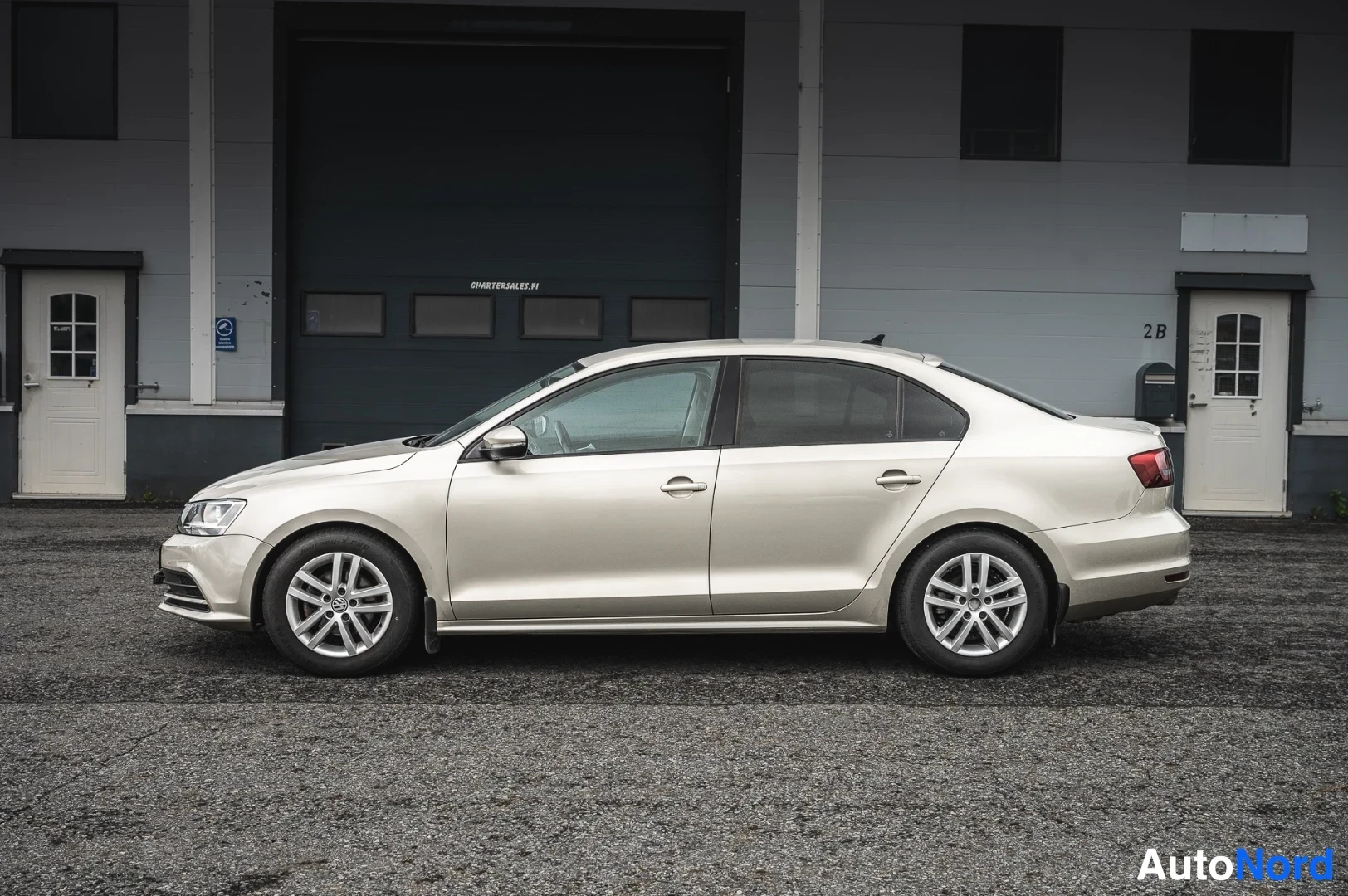 Etuviisto, nokka vasemmalle: Volkswagen Jetta -sedanin etukulma vasemmalta, vaaleanbeige runko.