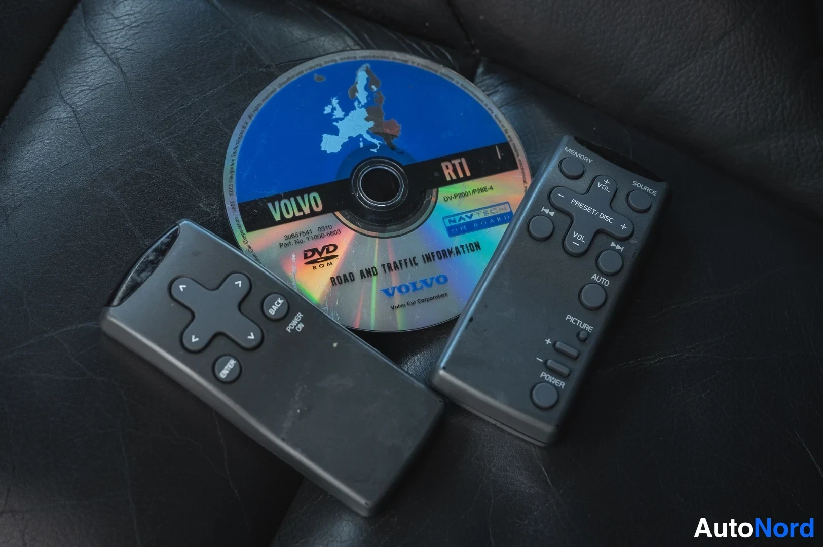 Muu: Kaksi kauko-ohjainta ja Volvo RTI -DVD-levy mustalla nahkapinnalla.