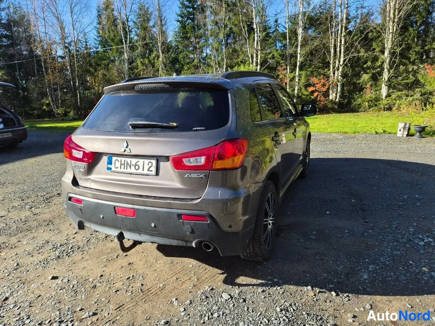 Takaviisto: Mitsubishi ASX:n takakulma autopaikalla; ruskea koripinta-ala, rekisteritunnus ja ASX-merkintä näkyvät.
