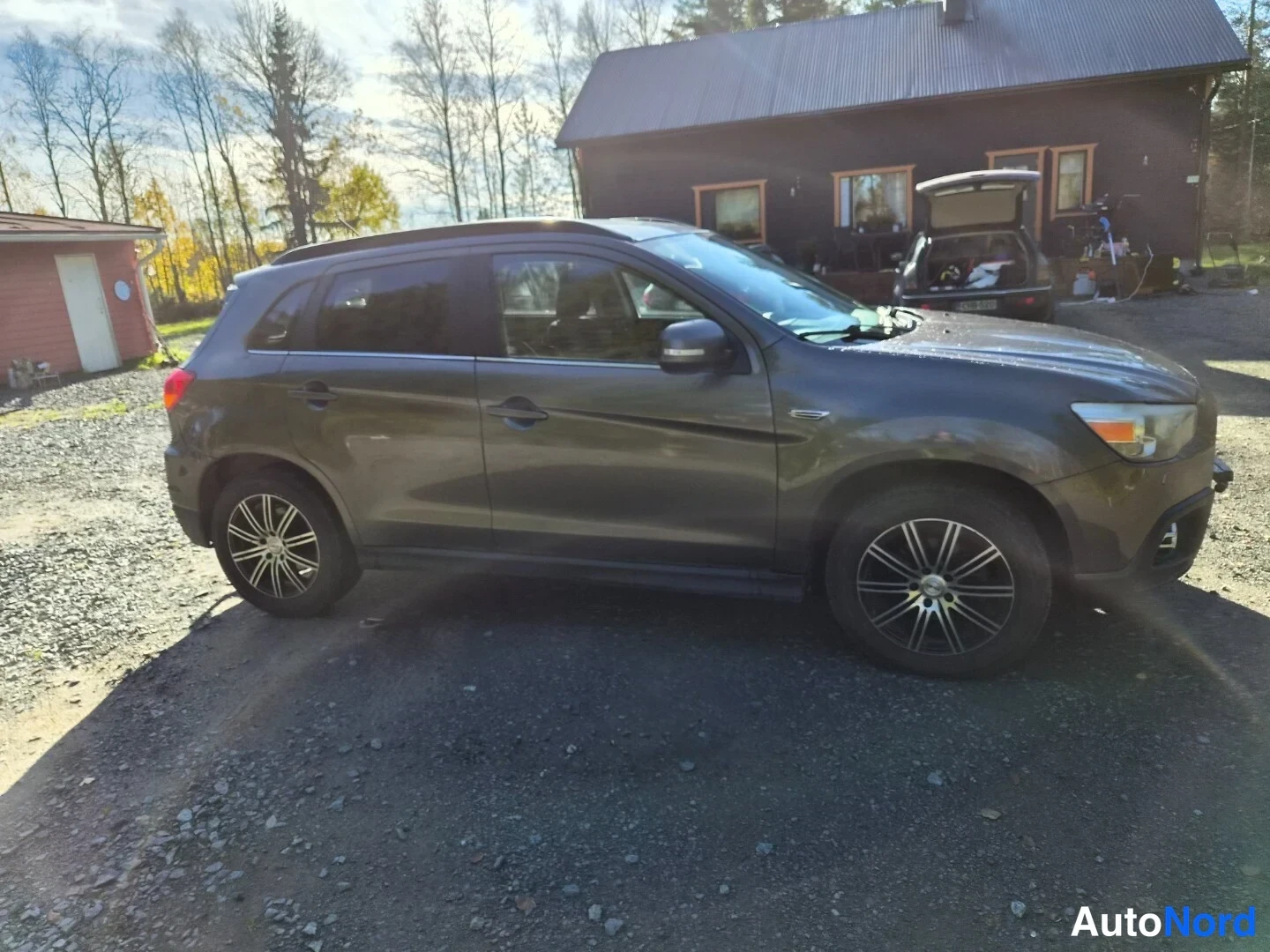 Etuviisto, nokka oikealle: Tummanharmaa Mitsubishi ASX kolmeneljänneskulmasta keula oikealla, keulasuojus ja keulakori näkyvissä.