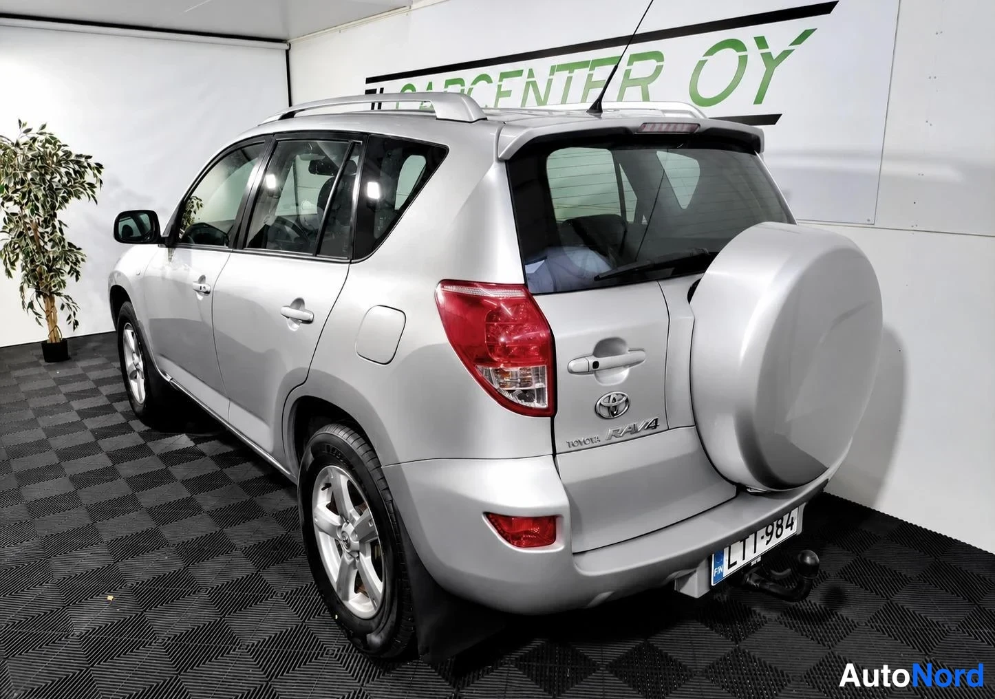 Takaviisto: Hopeanvärinen Toyota RAV4 takakulmasta vasemmalta, varapyörä takana ja rekisteritunnus.