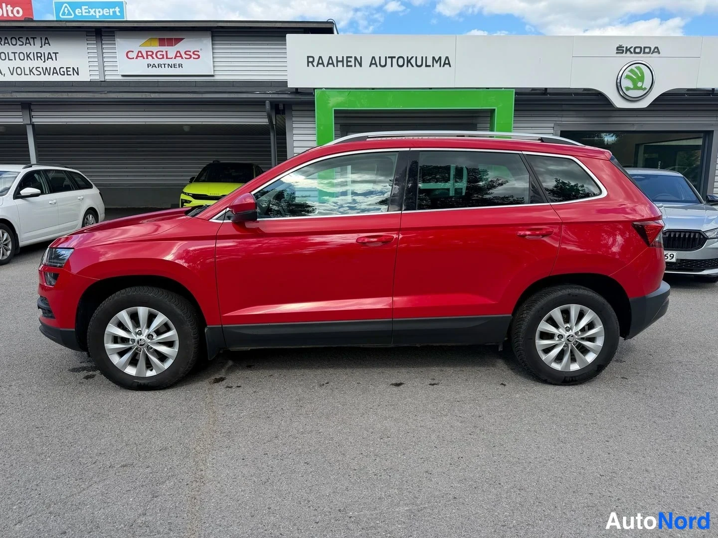Etuviisto, nokka vasemmalle: Punaisen Skoda Karoqin kylki näkyvissä sivukuvassa autoliikkeen edustalla.