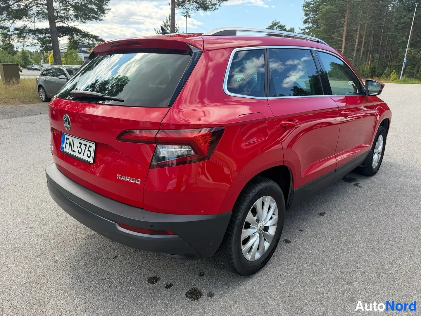Takaviisto: Punainen Skoda Karoq takaa kolmannes kuvassa, KAROQ-teksti ja rekisterikilpi näkyvissä.