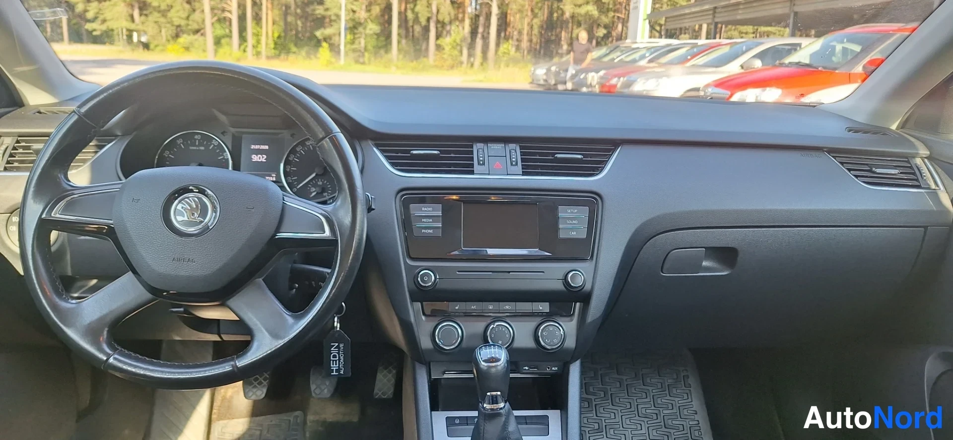 Yksityiskohta: Ohjaamo etupäältä: Skoda-ohjauspyörä, mittaristo ja keskikonsoli, jossa kosketusnäyttö ja manuaalivaihdekeppi.