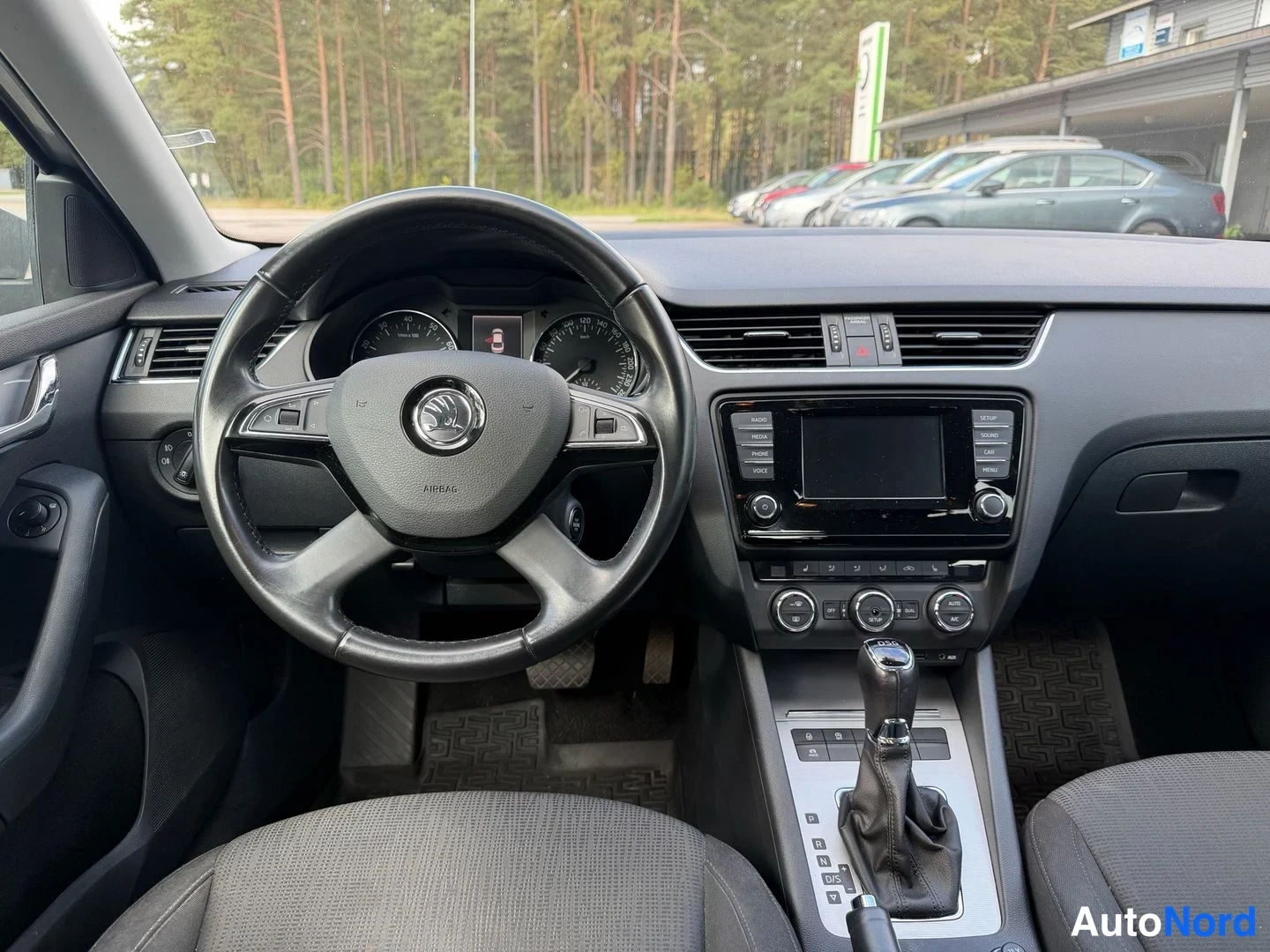 Muu: Ohjaamo vasemmalta ohjatulla autolla: mittaristo, monitoimiohjauspyörä, keskikonsolissa näyttö ja automaattivaihteen valitsin.