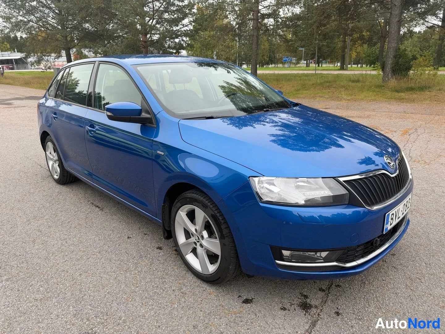 Etuviisto, nokka oikealle: Sininen Skoda Rapid Spaceback etusivulta oikeaan viistosti kuvattuna, rekisterikilpi näkyvissä.
