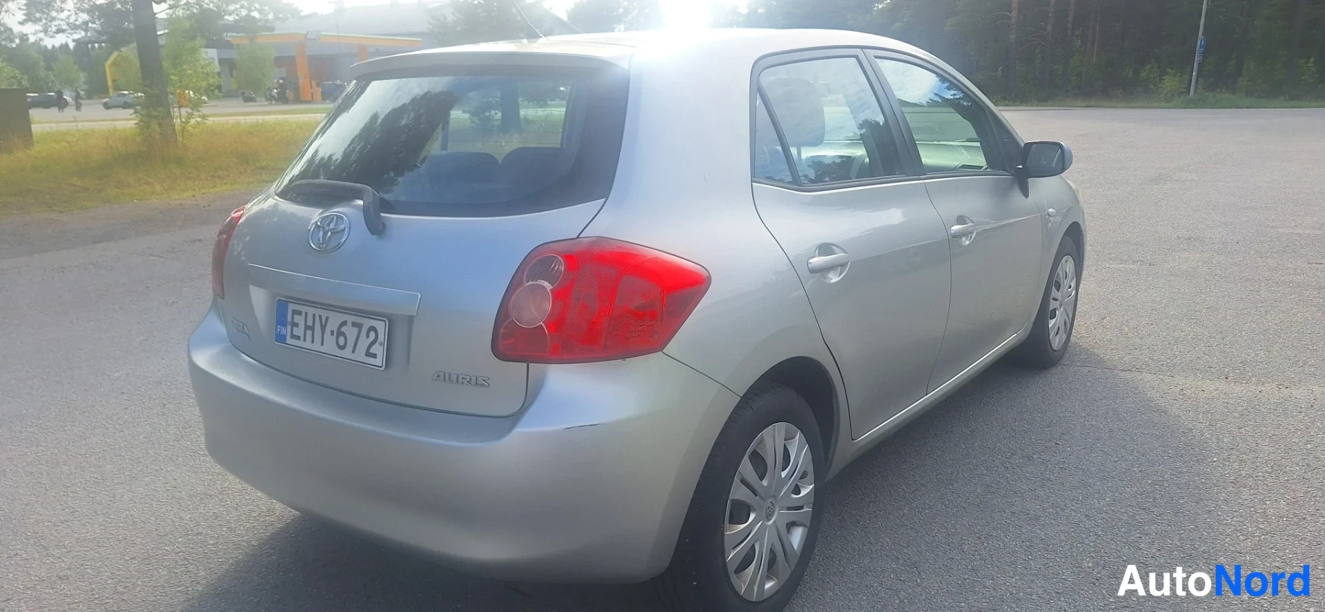 Takaviisto: Hopeanvärinen hatchback takaa kuvattuna; rekisterikilpi, Toyota-merkki ja punaiset takavalot näkyvät.
