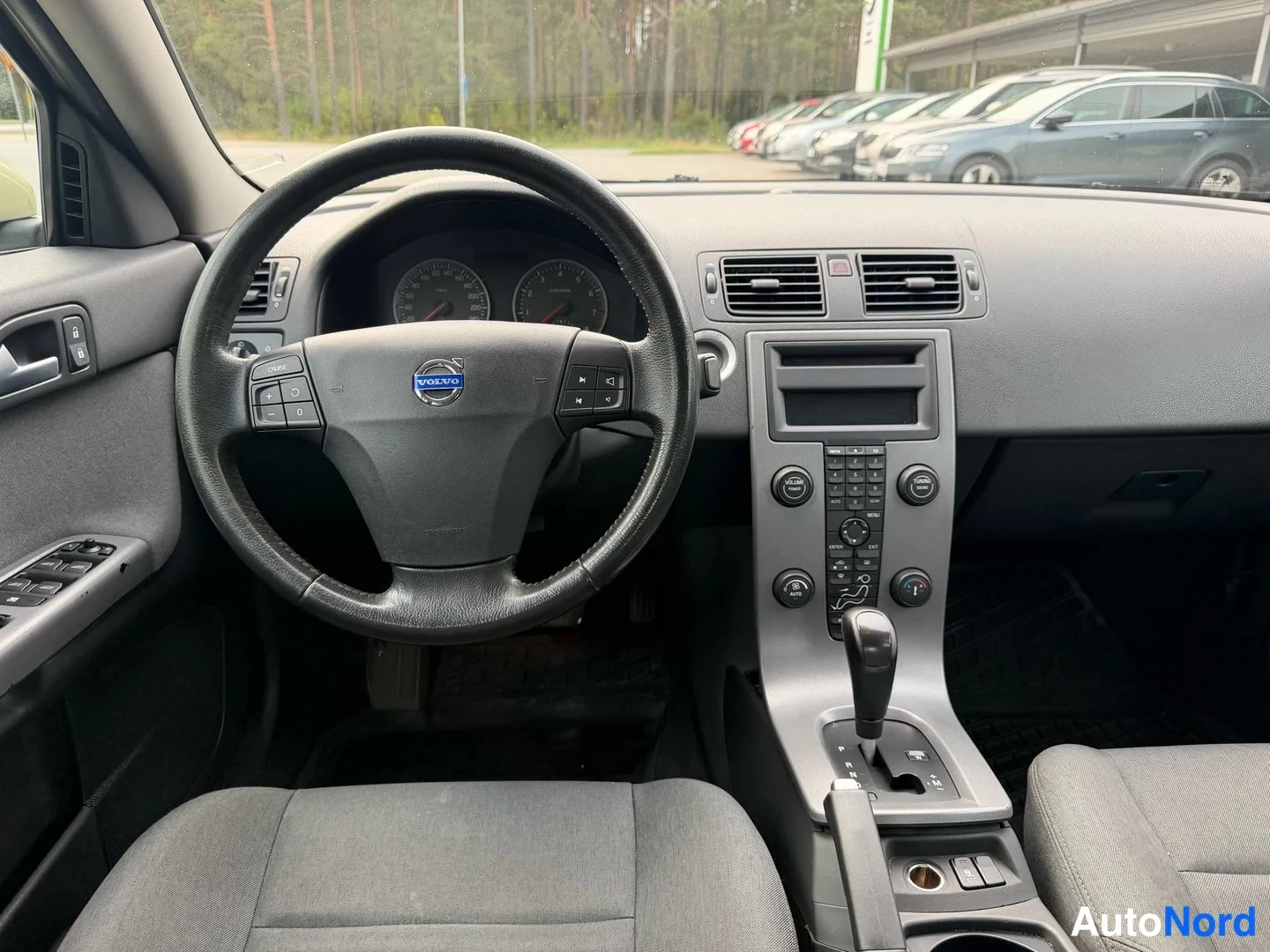 Edestä: Volvo S40:n etupenkkien näkymä kohti kojelautaa: ohjauspyörä, mittaristo ja keskikonsoli automaatinvaihteella.