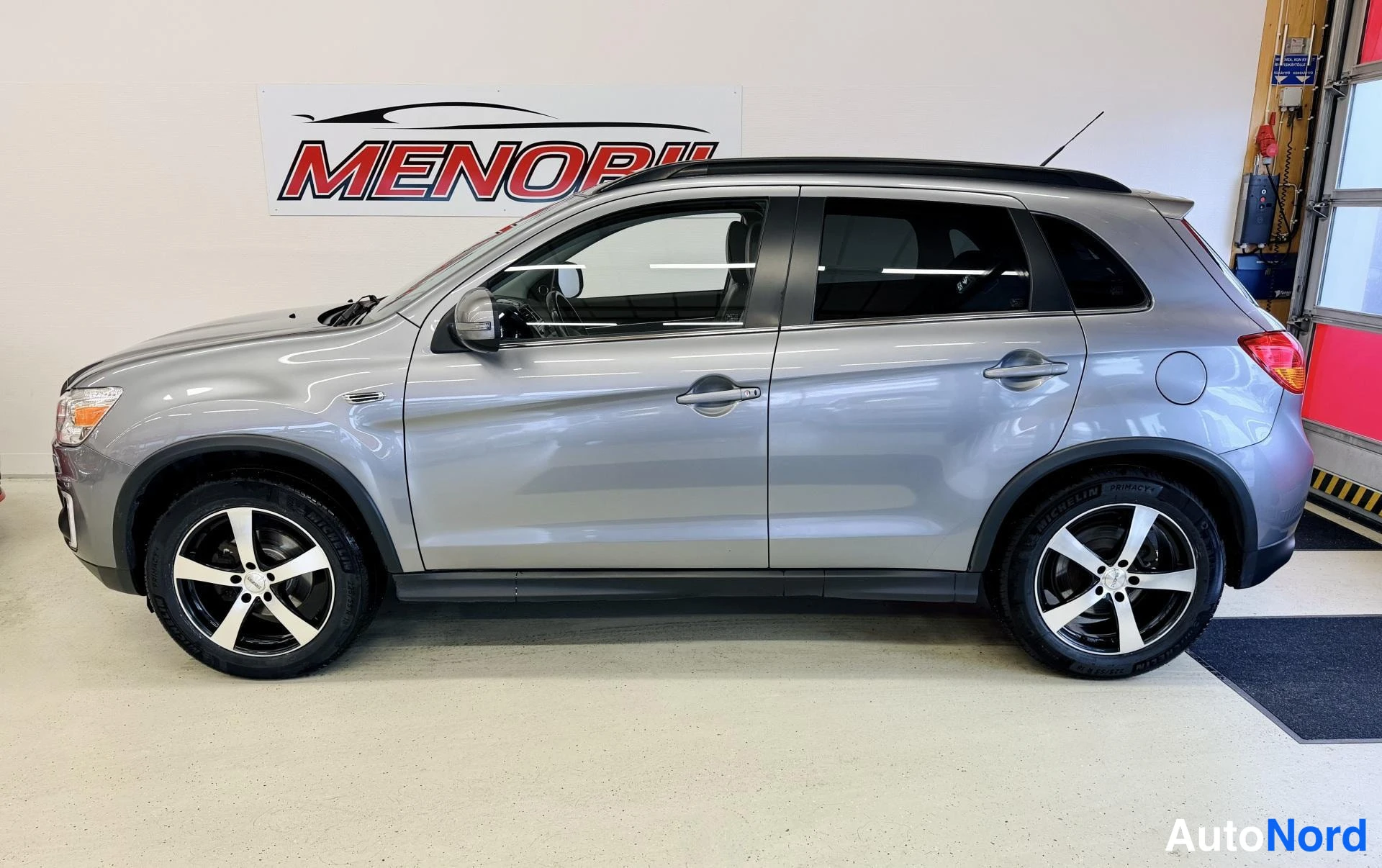 Sivulta: Harmaa Mitsubishi ASX vasen sivuprofiili sisätiloissa, takanasin pyörät ja kattokaaret.