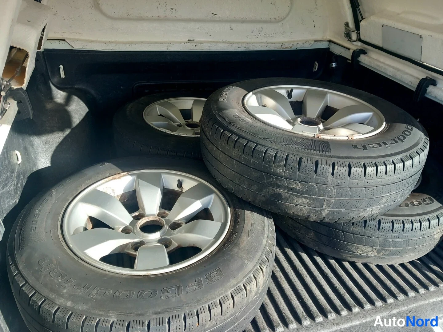 Yksityiskohta: Renkaita alumiinivanteilla lavassa lähikuvassa, BFGoodrich-merkintä rengassivussa.
