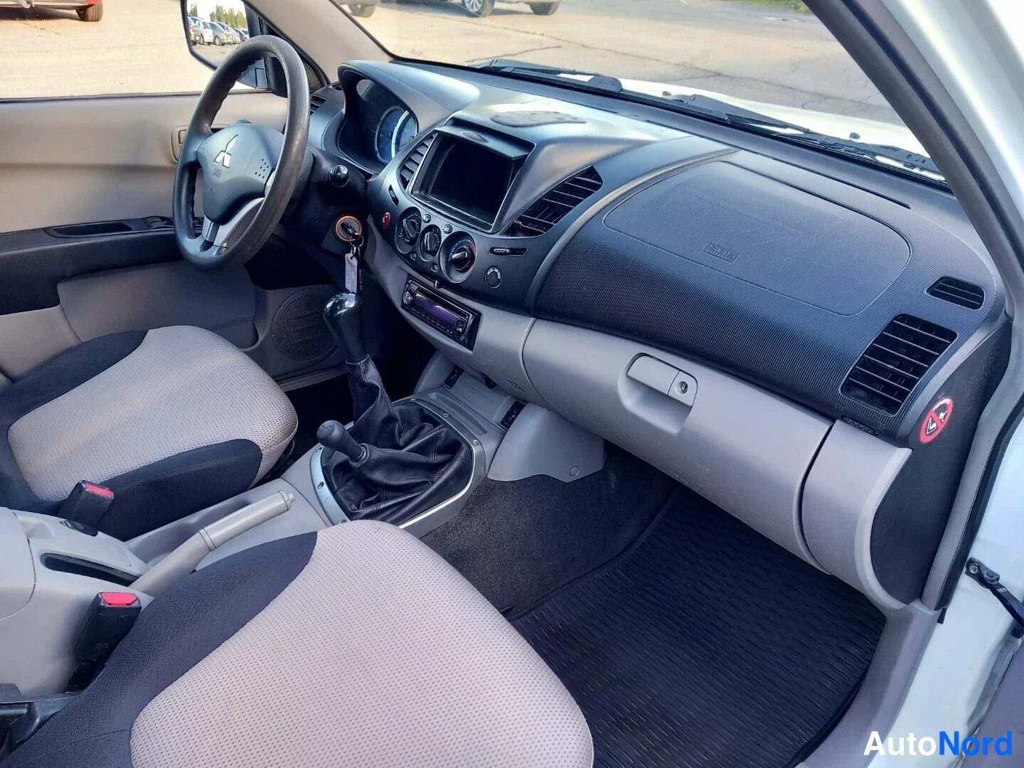 Muu: Auton sisätilat kuljettajan puolelta: Mitsubishi-ohjauspyörä, manuaalivaihteisto, radio ja tumma kojelauta.