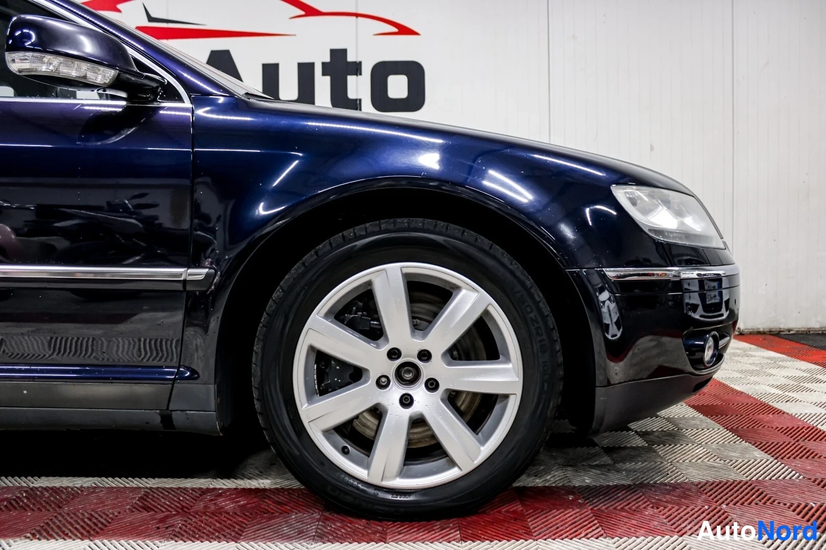 Etuviisto, nokka oikealle: Tummansinisen Volkswagen Phaetonin etusivu ja keula lähikuvassa, hopea moni-uravanne.