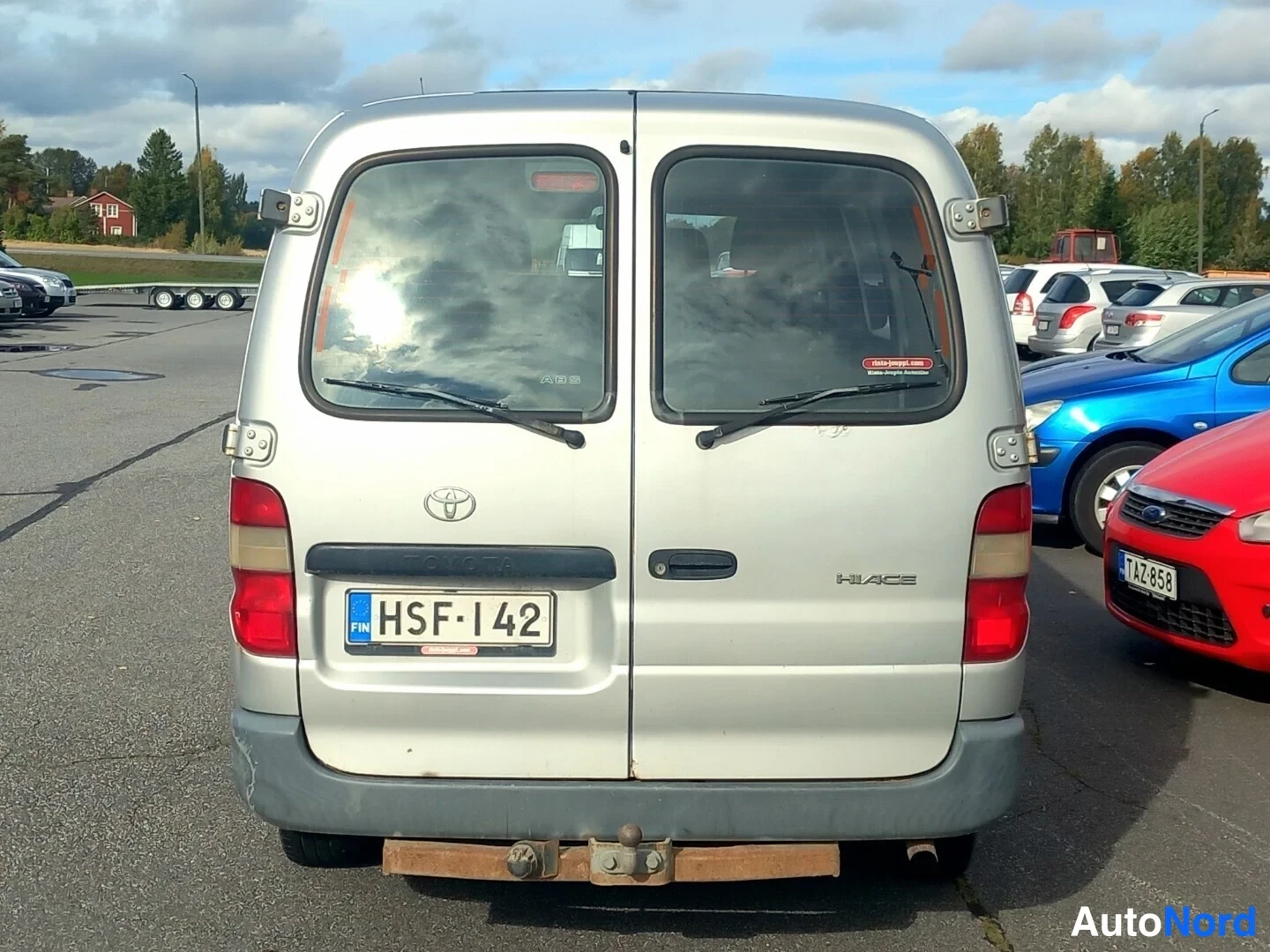 Takaa: Hopeanharmaan Toyota Hiacen perä suoraan takaa, kaksoistakaluukut, rekisterikilpi, alataso luukkujen yläpuolella.