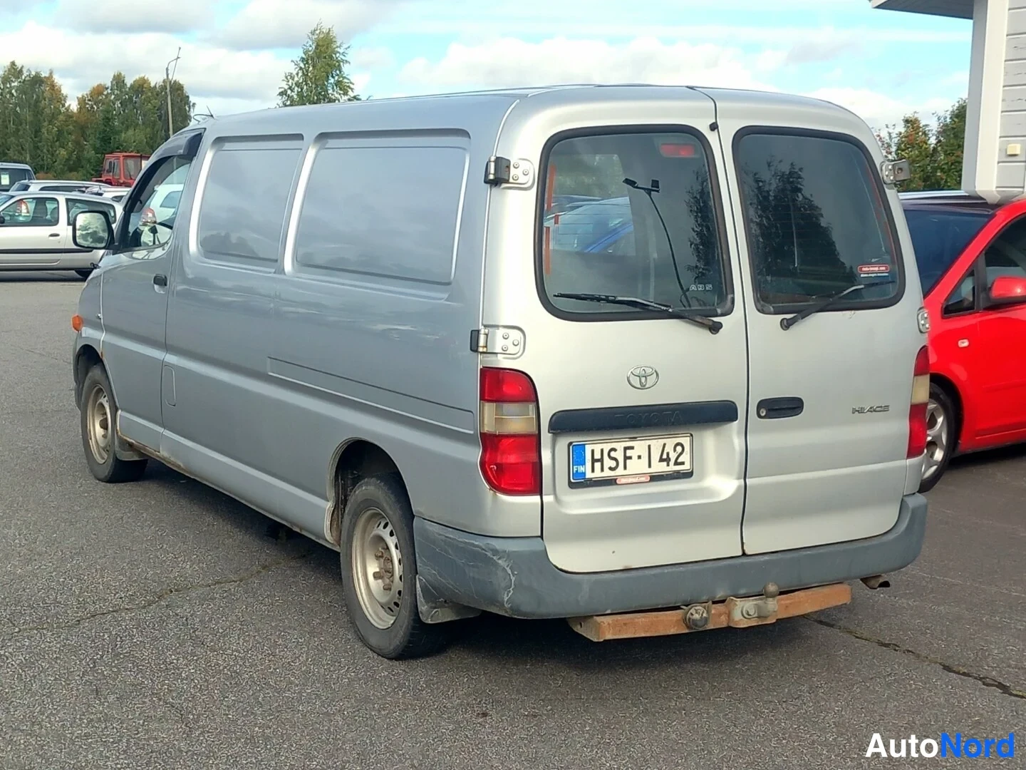 Takaviisto: Toyota Hiace -pakettiauton takaosa ja oikea kylki, rekisterikilpi, takakannessa Hiace-teksti.