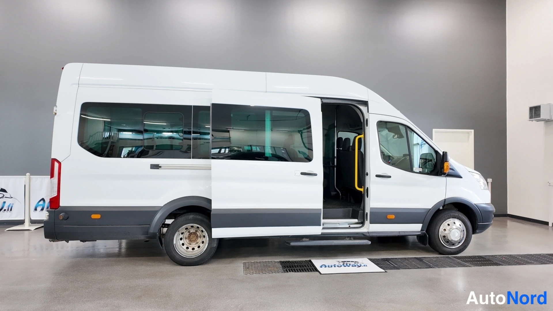 Sivulta: Valkoisen Ford Transit -bussin sivuprofiili, liukuova auki, kuvattuna sisätiloissa.