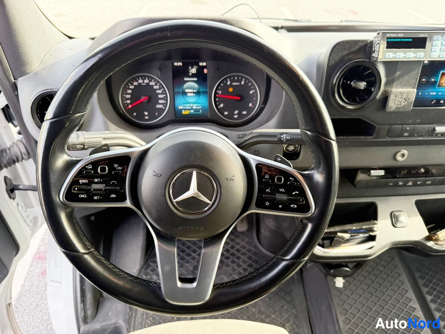 Muu: Ohjaamon ratin lähikuva, ratin keskiössä Mercedes-tähti, taustalla kojelauta.