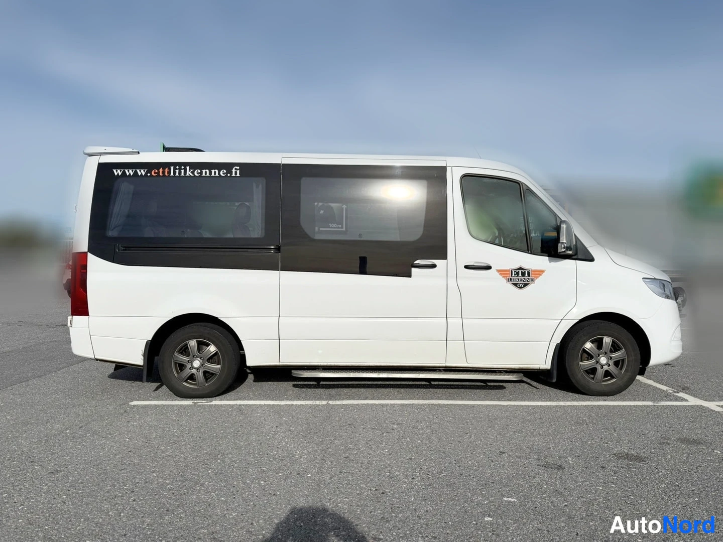 Sivulta: Mercedes-Benz Sprinter sivulta vasemmalta, kokovalkoinen pieni linja-auto.