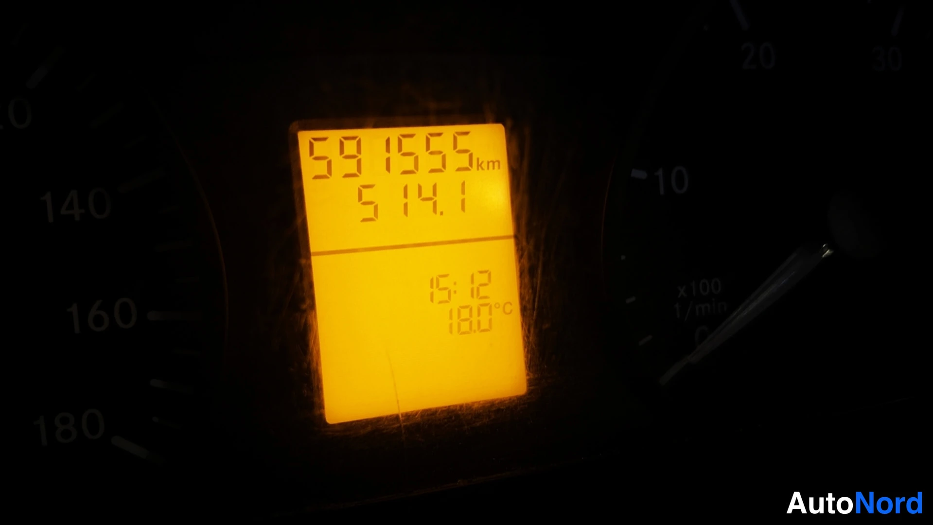 Yksityiskohta: Kojelautanäytön tumma lähikuva, jossa näkyy oranssi lukema 591555 km ja 5141.