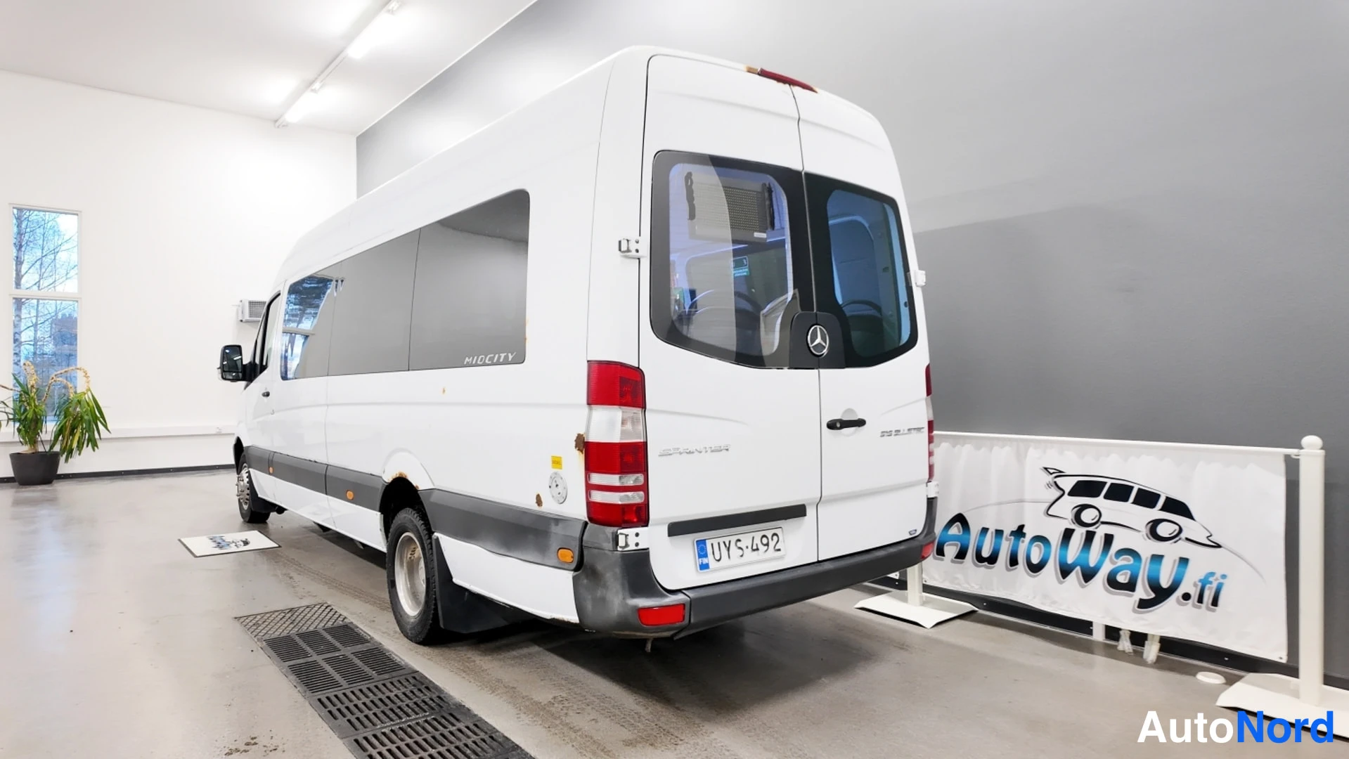 Takaviisto: Mercedes-Benz Sprinter -pakettiauto takaosaviistossa hallissa, takapää ja vasen kylki näkyvissä, takavalo ja rekisterikilpi suoraan kuvattuna.