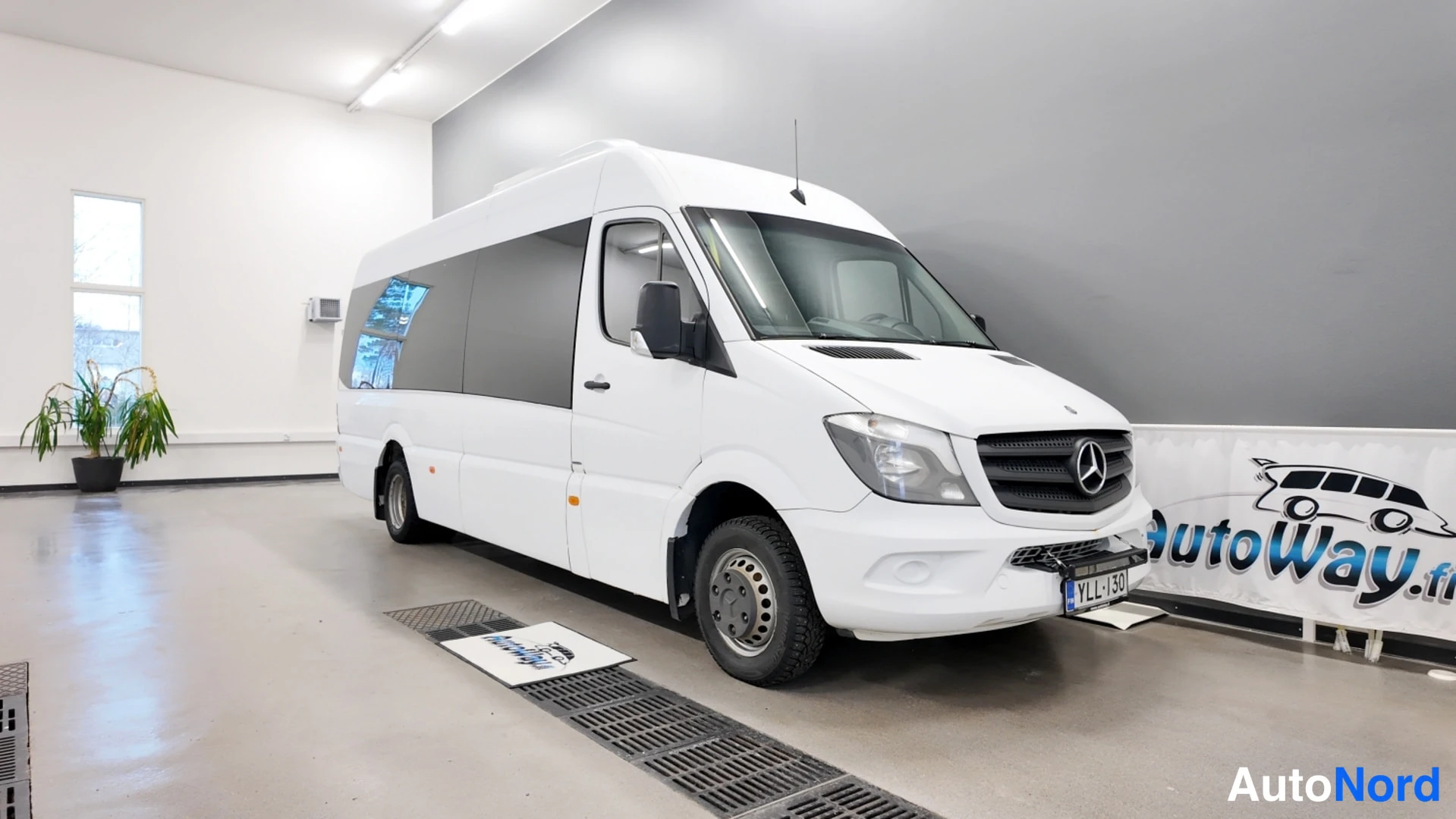 Etuviisto, nokka oikealle: Valkoinen Mercedes-Benz Sprinter -pakettiauto näkyvät keulakoriste ja kylki kuvan oikealla.