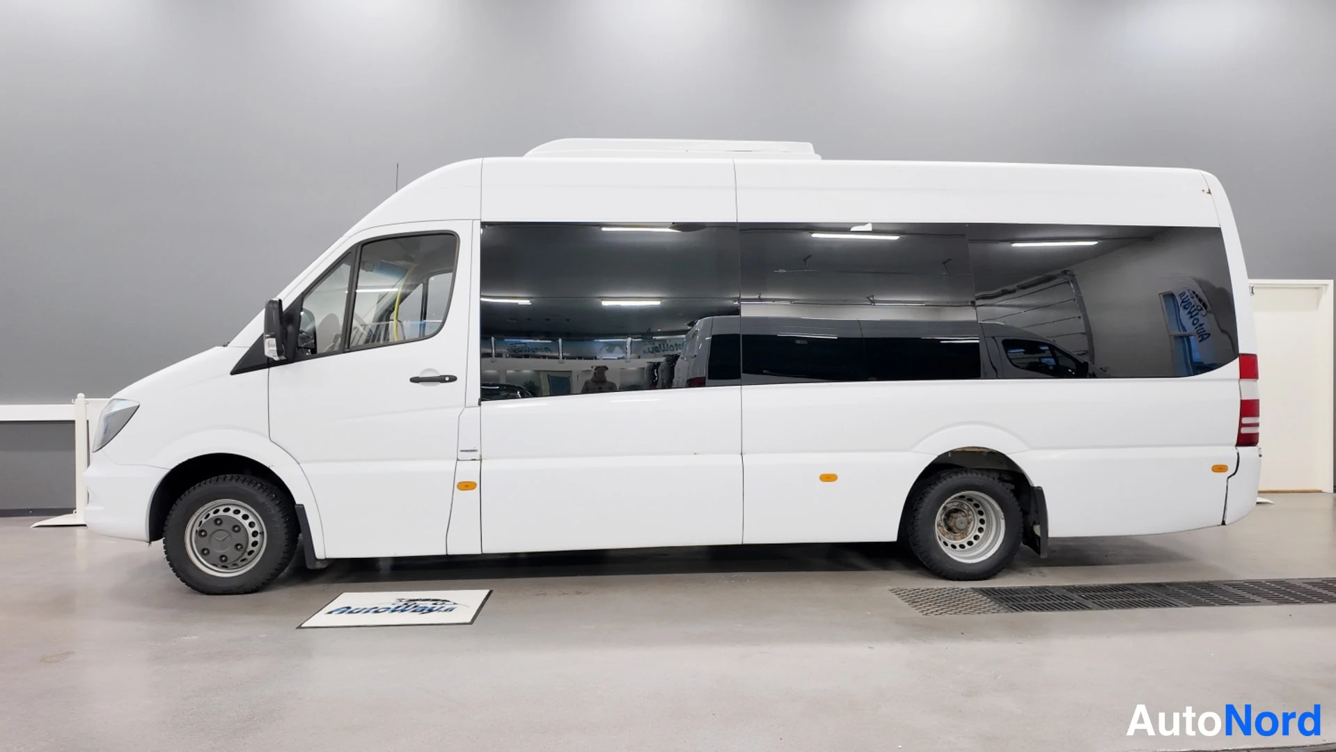 Sivulta: Valkoisen Mercedes-Benz Sprinter -pakettiauton sivuprofiili sisätiloissa.