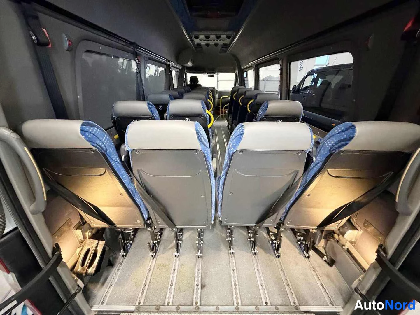 Sivulta: Mercedes-Benz Sprinter -auton sisätilat, rivissä selkänojat eteenpäin kääntyneitä penkkejä