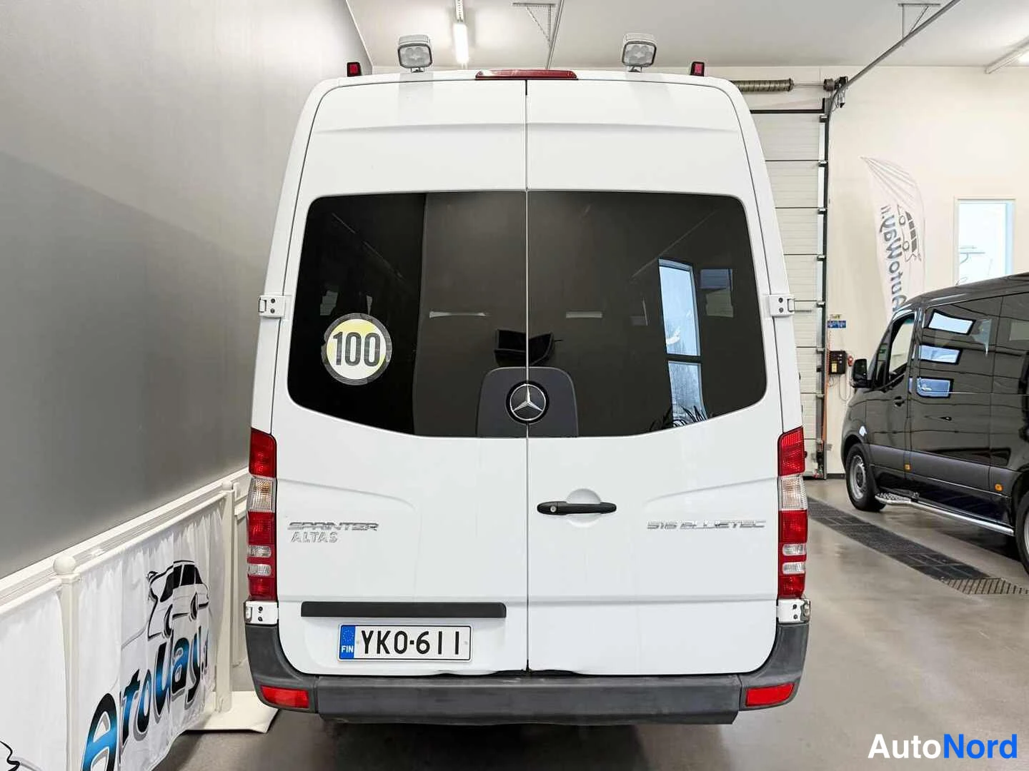 Takaa: Valkoisen pakettiauton takaosa suoraan takaa, takalasi, Mercedes-tähti ja rekisterikilpi näkyvissä.