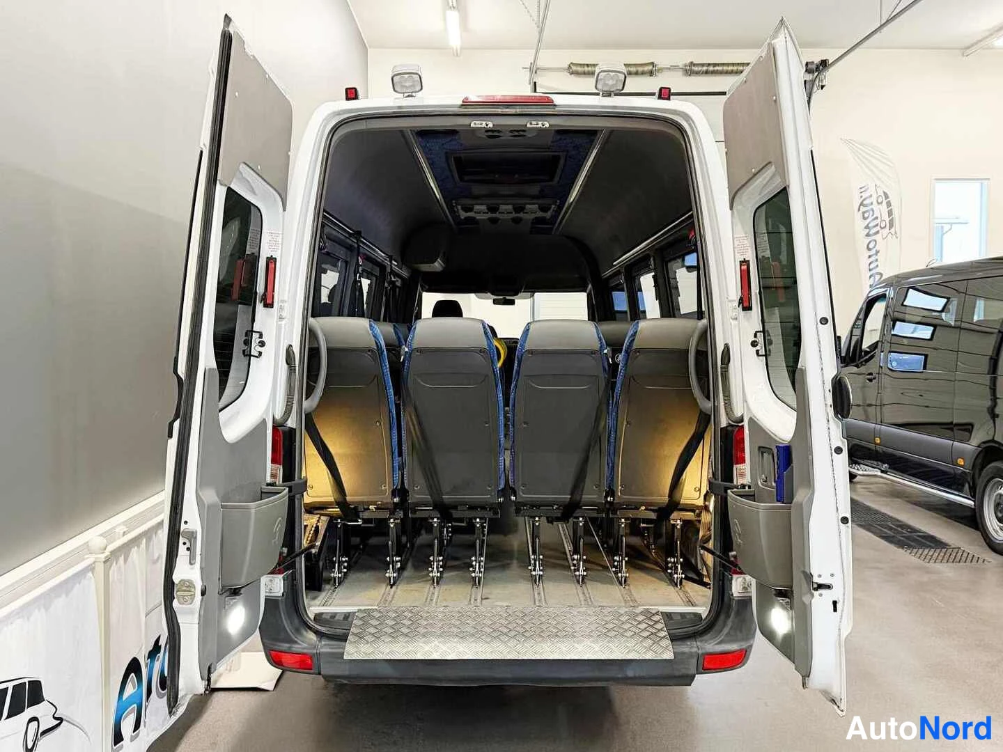 Takaa: Mercedes-Benz Sprinter -pakettiauton takaluukut auki, kuva lavetista ja rivissä olevista penkeistä