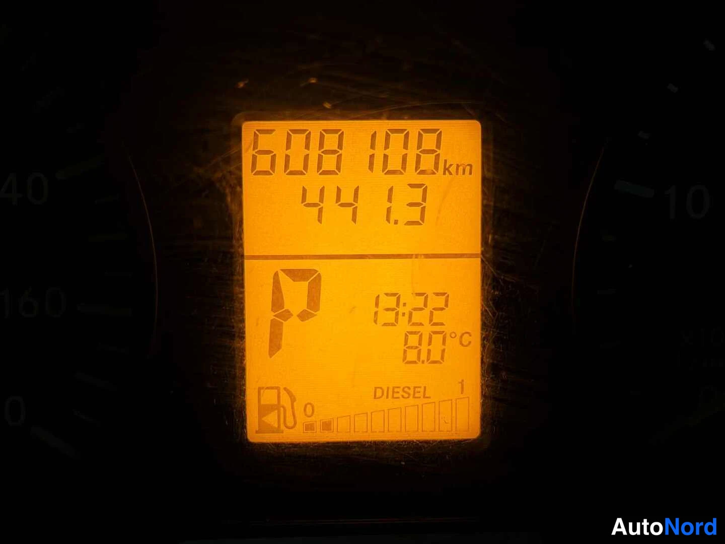 Yksityiskohta: Kojelaudan näyttö näyttää matkamittarin lukeman 608108 km, vierintämatkan 44.3, vaihteen P, ajan 13:22, lämpötilan 00°C ja Diesel 1 -polttoainetankin matalan ta