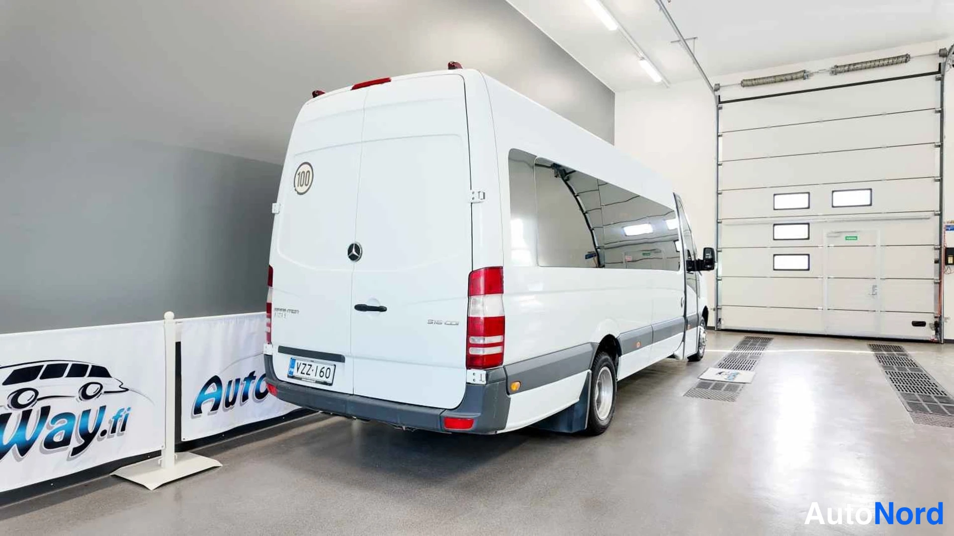 Takaviisto: Valkoinen Mercedes-Benz Sprinter -pakettiauto takaa-oikealta kuvattuna autotallissa