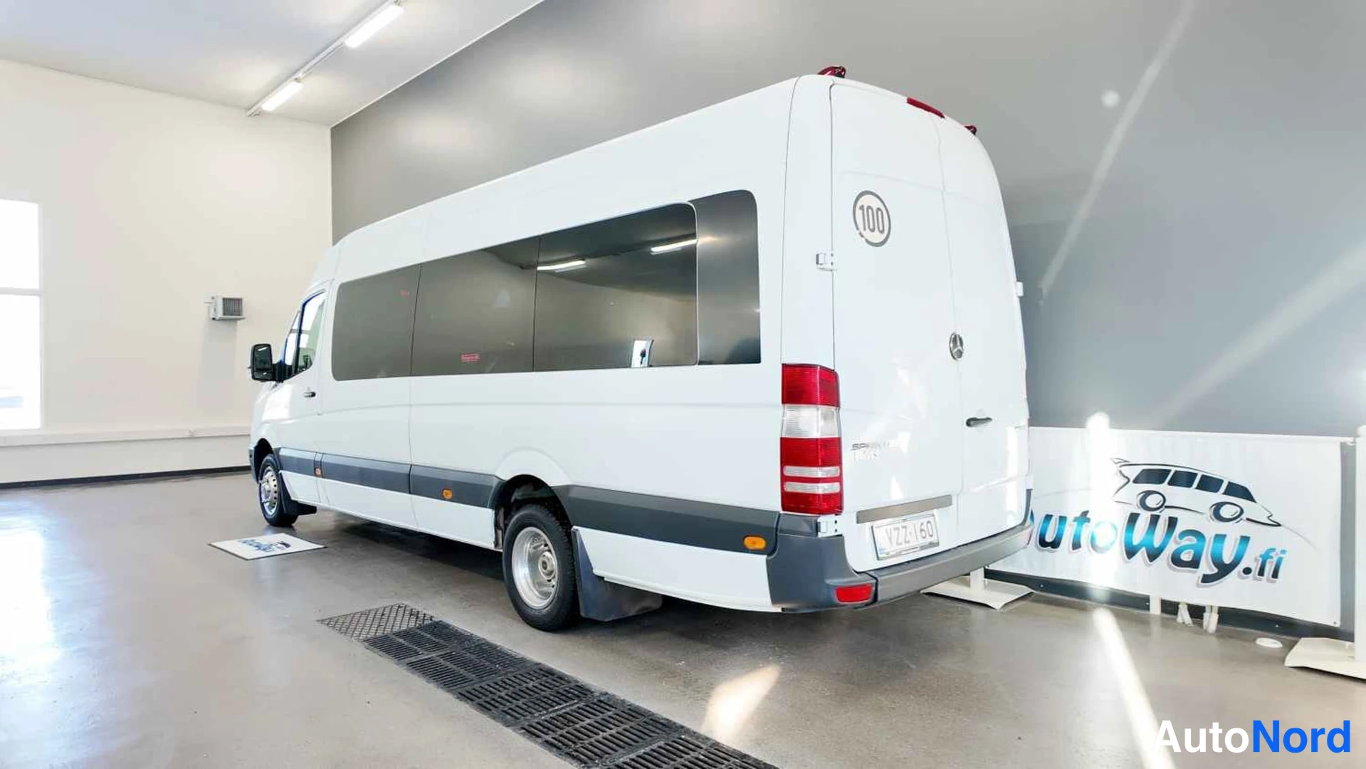 Takaviisto: Mercedes-Benz Sprinter -pakettiauto takaa sivulta kuvattuna valkoisena showroomissa, takaovet ja takavalo näkyvät.