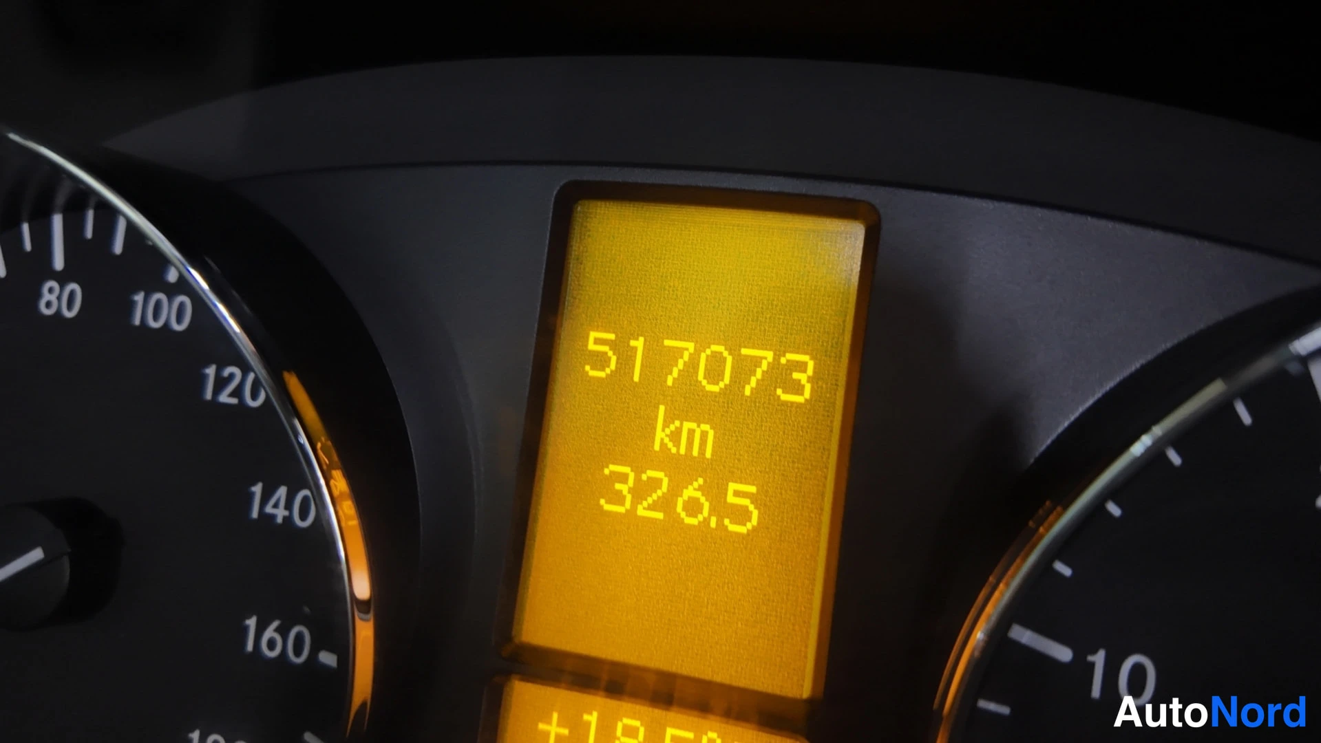 Yksityiskohta: Kojelaudan näyttö, jossa näkyy kokonaismatka 517073 km.