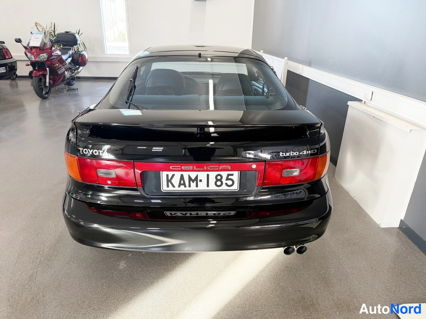 Takaa: Mustan Toyota Celican takapää; rekisterikilpi, Toyota-teksti ja kaksi pakoputkea.