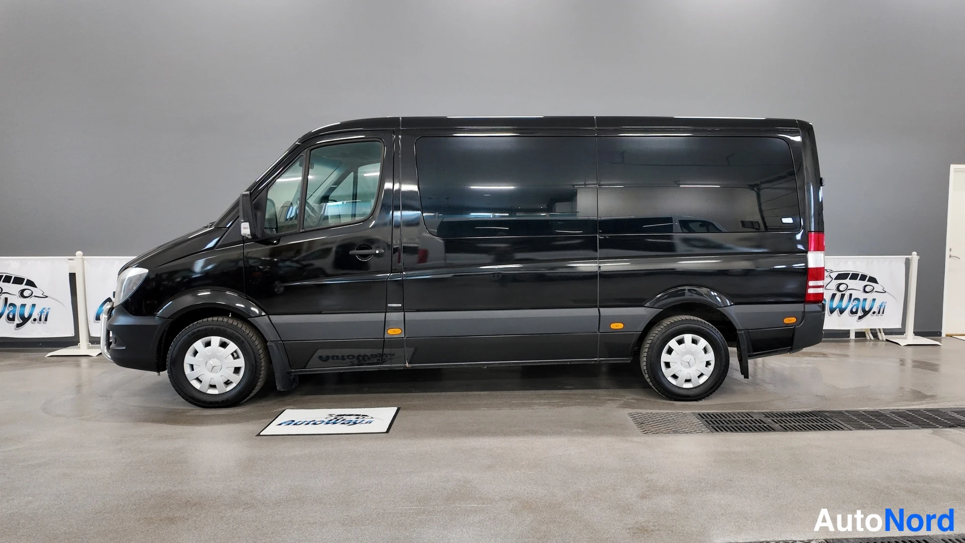 Sivulta: Mustan Mercedes-Benz Sprinter -pakettiauton sivuprofiili sisätiloissa