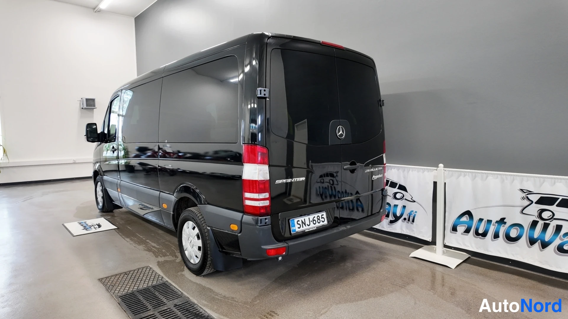 Takaviisto: Mustan Mercedes-Benz Sprinter -pakettiauton takakulma