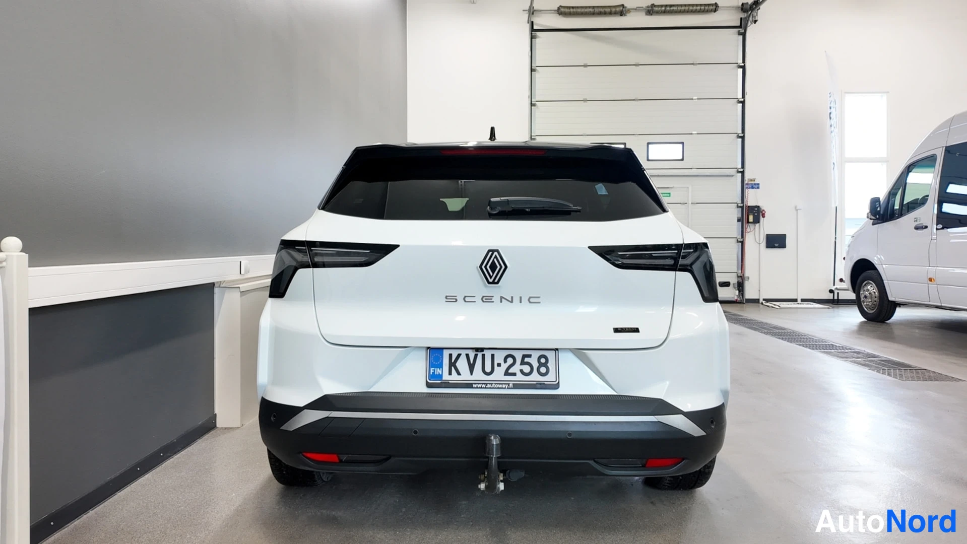 Takaa: Renault Scenicin takanäkymä valkoisena, rekisterikilpi,coupling-nostokoulu näkyy takapuskissa.