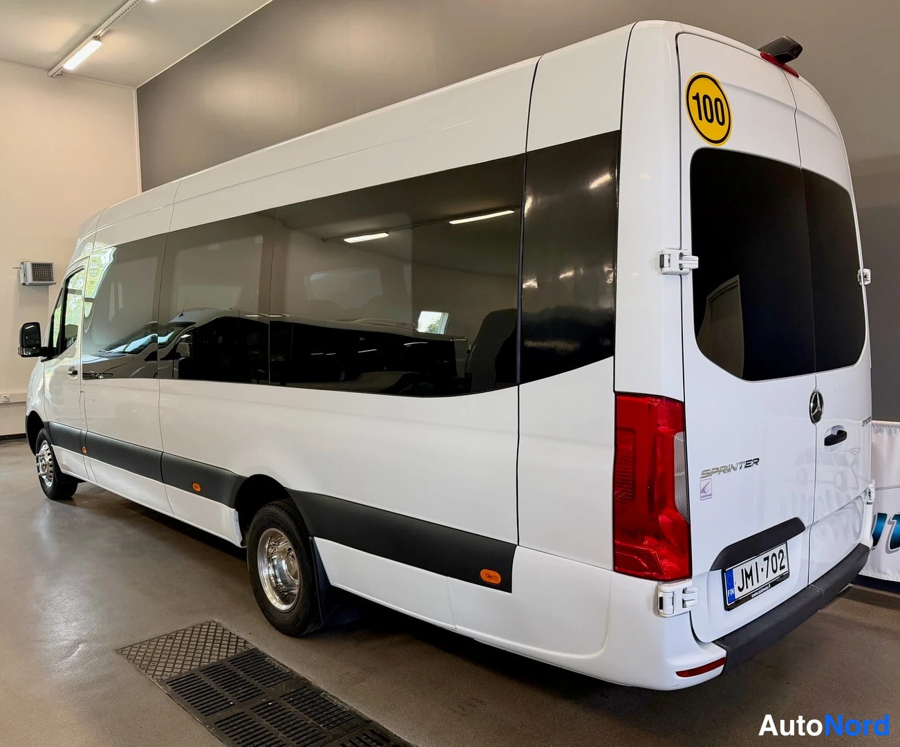 Takaviisto: Mercedes-Benz Sprinter -pakettiauton takaosa ja vasen sivu, valkoinen koritunnus ja keltainen 100-vuotismerkintä.