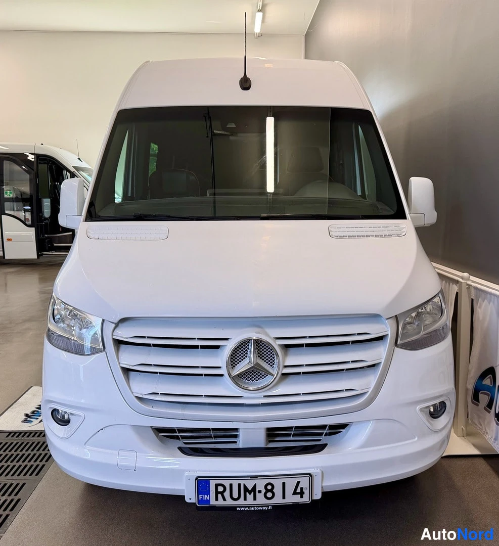 Edestä: Ajetun auton valkoinen etupää suoraan edestä, Mercedes-tähti etusäleikössä ja rekisterikilpi.