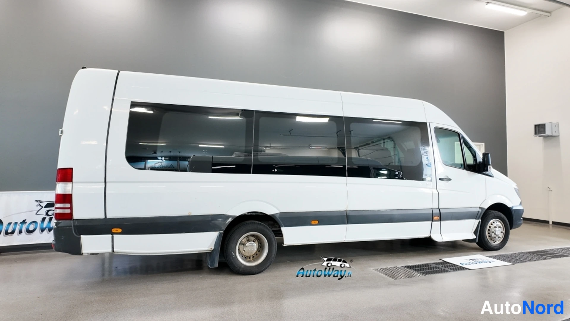 Etuviisto, nokka oikealle: Valkoisen Mercedes-Benz Sprinter -auton sivukulma ja keulan nokka oikealla sisätiloissa.