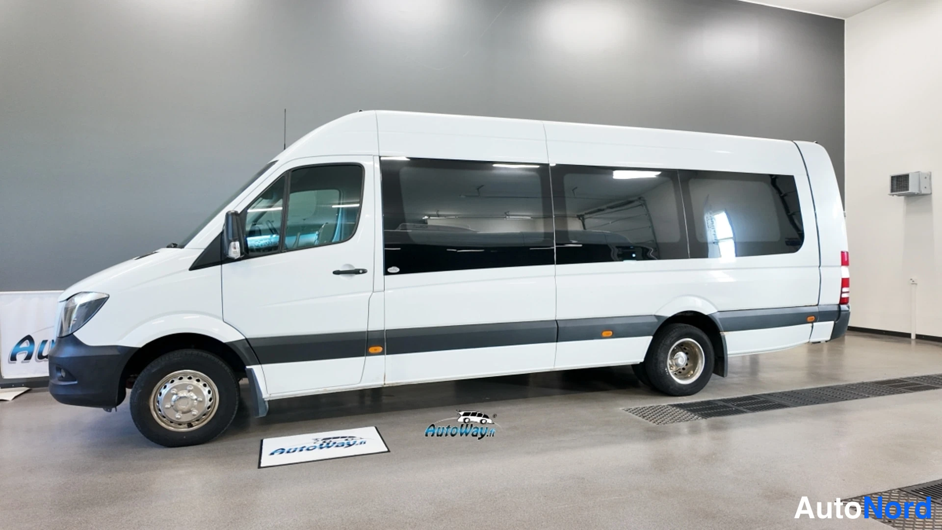Sivulta: Valkoinen Mercedes-Benz Sprinter -auto sivulta, koko kylki näkyvissä sisätilassa.