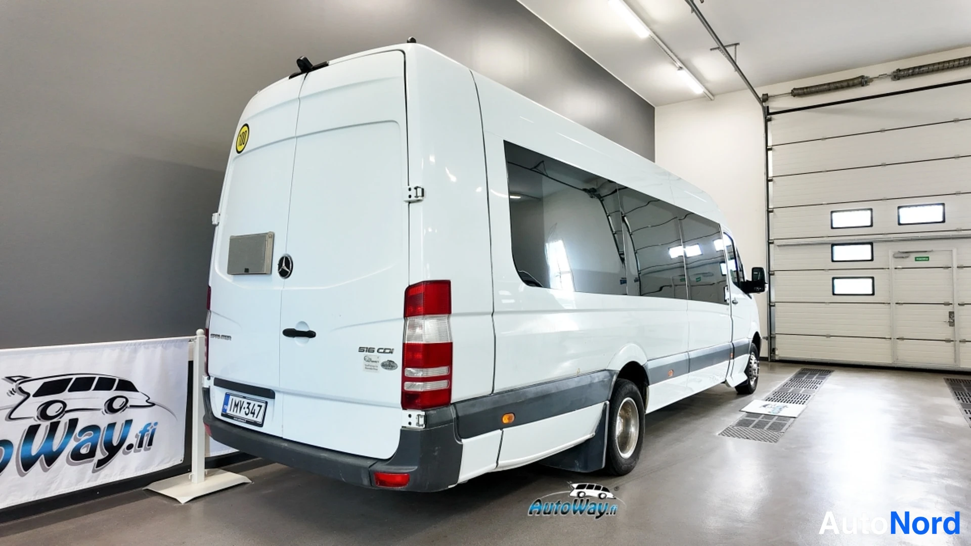 Takaviisto: Valkoisen Mercedes-Benz Sprinter -auton takakulma ja sivuprofiili sisätiloissa, perä vasemmalla.