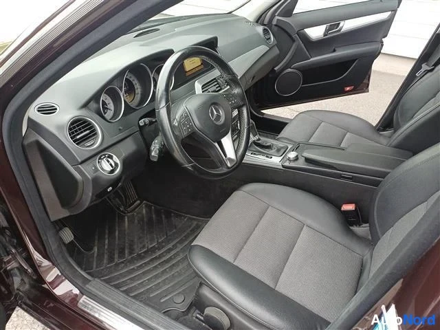 Muu: Auton sisätila ohjaamon puolelta: musta nahkapenkit, Mercedes-ratti, instrumentit ja automatic-kytkin.