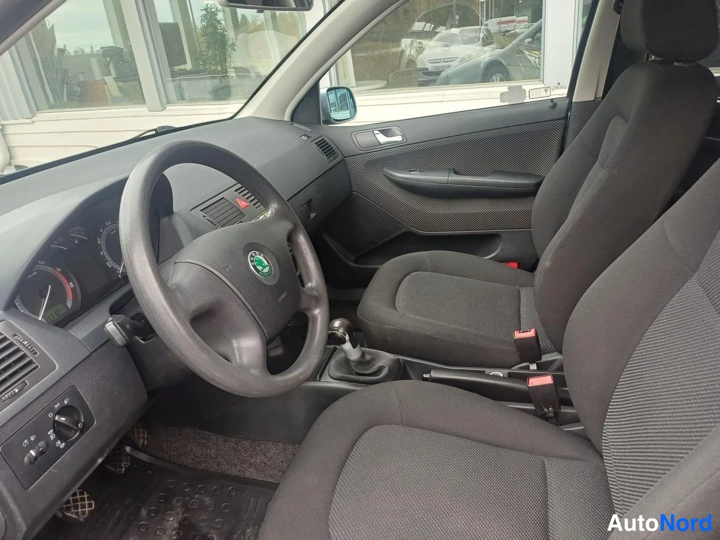 Muu: Auton ohjaamo vasemmalta: Skoda-ohjauspyörä, tummat kangasistuimet ja manuaalivaihtokeksi.