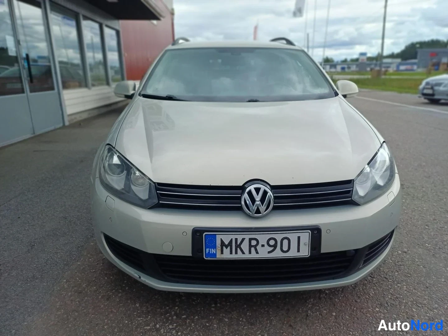 Edestä: Edestä kuvattu hopeanvärinen auto, jonka rekisterikilpi on.
