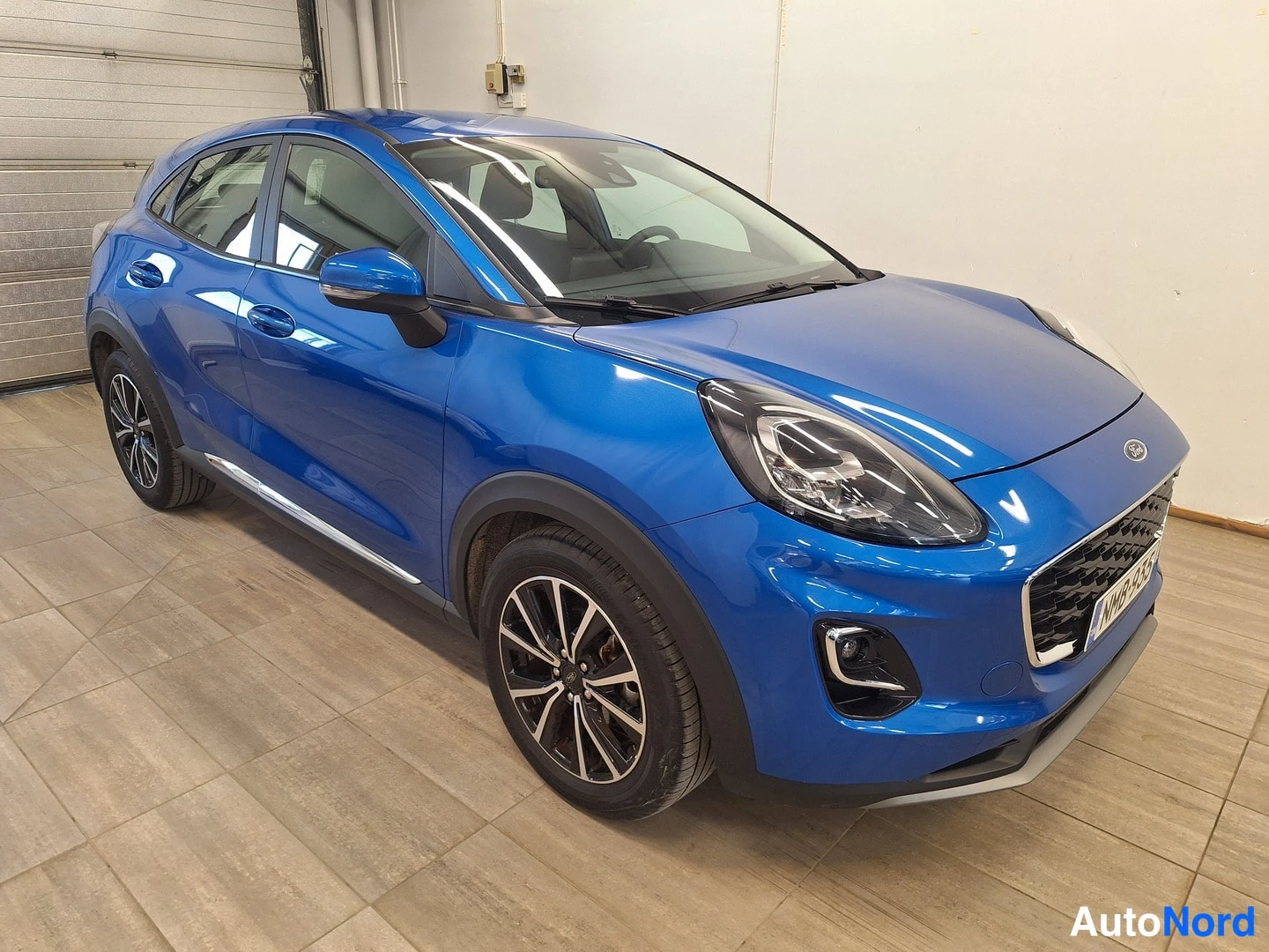 Etuviisto, nokka oikealle: Sininen Ford Puma kulmaperspektiivistä keulaa ja vasenta sivua näkyen sisätiloissa.