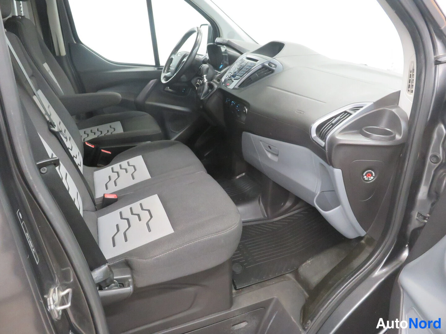 Muu: Ford Transit Custom -pakettiauton sisätilat: kaksi etuistuinta, ohjauspyörä ja kojelauta kuvattuna avatusta sivuovesta.
